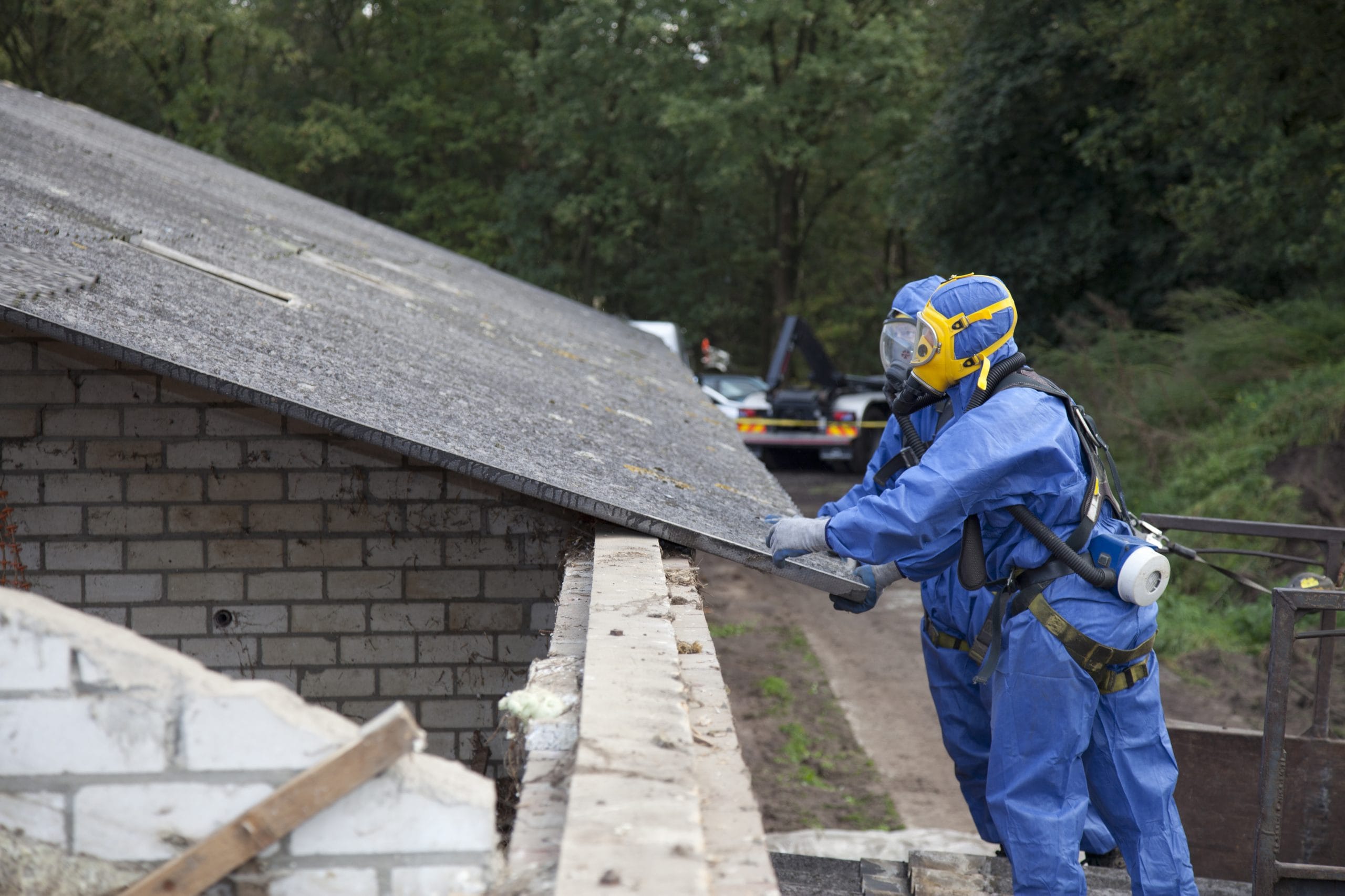 Specialist asbestos removal operatives in full PPE safely removing a roof containing asbestos.